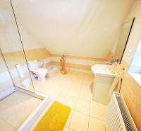 A bright bathroom in a cottage with a bathtub and a sink, complemented by light tiles.