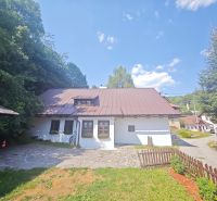 A cottage in Špania Dolina, surrounded by nature, with a stone path and a wooden fence.