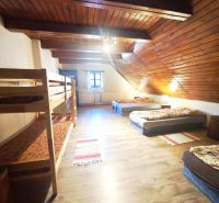 An attic room in a cottage with beds and a wooden decor floor.