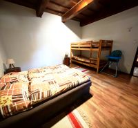 A bedroom in a cabin with a double bed, a bunk bed, and a floor with a wooden decor.