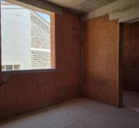 An unfinished building interior with brick walls and a window opening, without flooring.