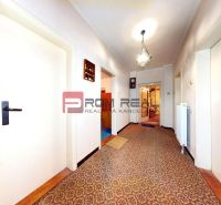 A hallway of a family house with a carpet, light walls, and a decorative chandelier.