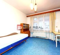 A room in a family house with a bed, a blue carpet, and a desk.