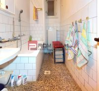 Bathroom with a bathtub, sink, and towel racks in a family house.