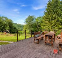 A cottage in Píla with a wooden terrace, wooden furniture, and a view of the trees and a swing.