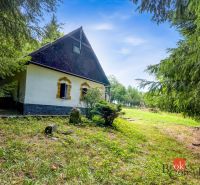 A cottage in Píla surrounded by greenery and coniferous trees, ideal for relaxation.