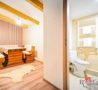 A cottage with wooden furniture and a floor with a wooden decor, next to a bathroom.