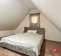 Attic bedroom in a cottage with a bed and a wooden decor floor.