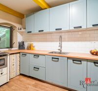 A kitchen in a cottage with blue cabinets, white tiles, and a wood-patterned floor.