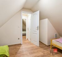 A room in a cottage with a wooden decor floor and a single bed.
