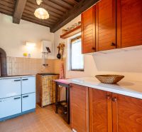 A kitchen in a cottage with a wooden cabinet and a stove, floor with brown decor.