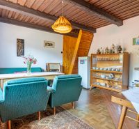 The interior of a cabin with green armchairs, a dining table, and a cabinet with dishes.