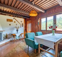 The interior of the cabin with wooden decor, a fireplace, and flowers on the table feels cozy.