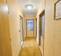 A hallway in a family house with a beige carpet and wooden doors.