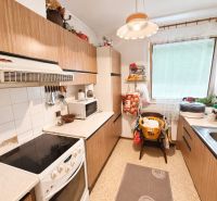 The kitchen in the family house has simple furniture with a wooden decor and white appliances.