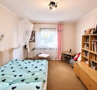 Room of a family house with a bed, bookshelf, and colorful accessories.