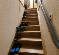 A staircase with a wooden decor floor full of shoes in a family house.