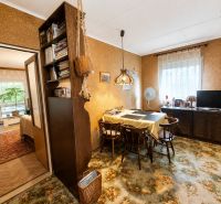 A dining room in a family house with wooden decor on the floor and a carpet with a floral pattern.