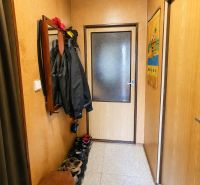 A hallway in a family house with a clothes rack and a shoe cabinet, neutral tones.
