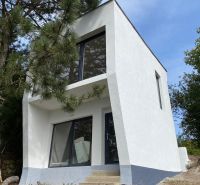 A modern white cottage in Šahy surrounded by nature and pine trees.