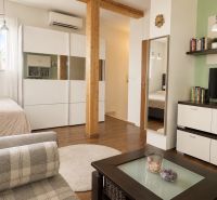 Living space in a one-room apartment with a wood-patterned floor and modern furniture.