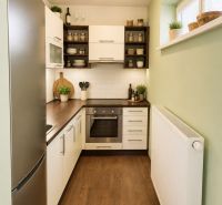 A kitchen in a studio apartment with a wooden decor floor and built-in appliances.