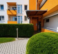 A colorful facade of a building surrounded by green shrubs on Cherry Street in Chorvátsky Grob.