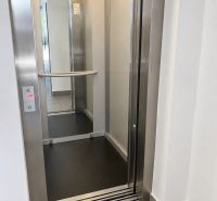Opening elevator doors with a steel frame and a mirror inside.
