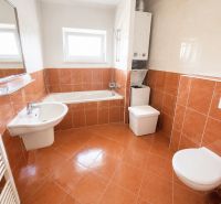 A bathroom with a bathtub, sink, toilet, and washing machine in a studio apartment.