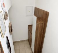 A staircase with storage space in a studio apartment, white wall, wooden decor.
