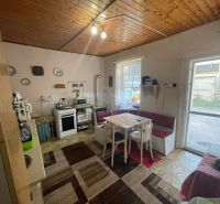 A kitchen in a family house with a dining table, carpets, and a wooden ceiling.