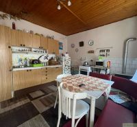 A kitchen in a family house with a wooden decor, a dining table with chairs and a couch.