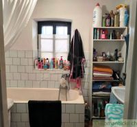 Bathroom in a family house with a bathtub, shelves, and various toiletries.
