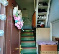Entrance to the family house with a staircase, storage spaces, and fresh flowers.