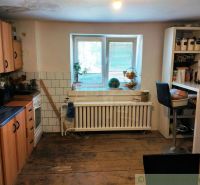 A kitchen in a family house with a wooden decor floor, equipped with appliances and furniture.