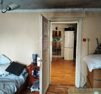 The interior of a family house with a bed and a view of the kitchen through open doors.