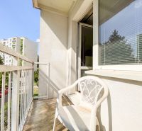 Balcony of a 1-room apartment in Trenčín on Halalovka with a plastic chair and a view.