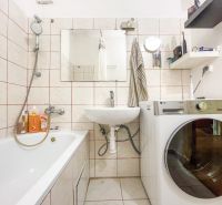 Bathroom with a bathtub, washing machine, and sink in a studio apartment.