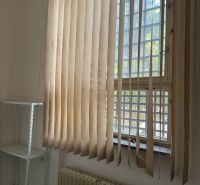 Offices with vertical blinds and a shelving unit, floor with wood decor.