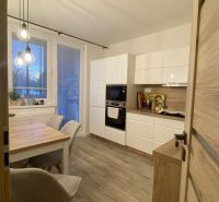 A kitchen in a 3-room apartment with a wooden decor floor and a dining table.