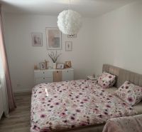 A bedroom with a bed, floral bedspread, and wood-patterned flooring in a 3-room apartment.