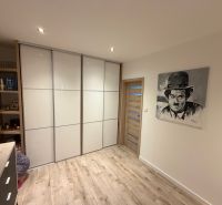 A room in a 3-room apartment with a wooden decor floor and a picture on the wall.