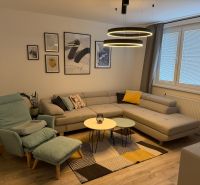 Living room with a gray sofa, armchair, and decorative paintings in a three-room apartment.