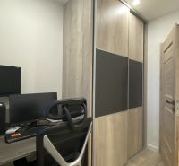 A workspace with a chair, desk, computer, and cabinet with wooden decor in a 3-room apartment.