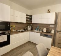 A kitchen in a 3-room apartment with white cabinets and a wood-patterned floor.