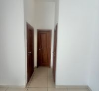 White walls with wooden doors and tiled floors in commercial spaces.