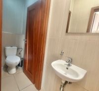 A small bathroom in commercial premises with a toilet, sink, and mirror.