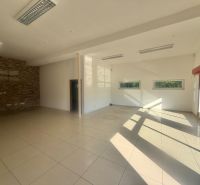 Spacious commercial spaces with large windows, white walls, and tiled floors.