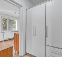 A large wardrobe, windows, and a wooden decor floor dominate the 1-room apartment.