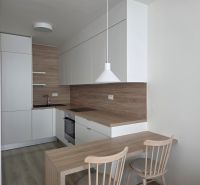 A kitchen with white cabinets and wooden decor in a two-room apartment.